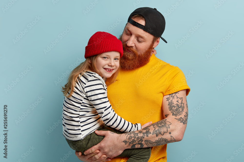 Wall mural family portrait of handsome caring young foxy dad carries small girl on hands, expresses love, spend