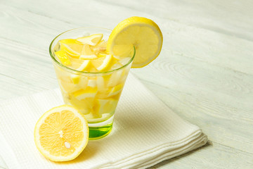 Water with lemon. Lemonade with lemon slices on white wooden background.