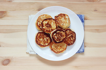 plate with cheesecakes or pancakes in the center of the table, top view.