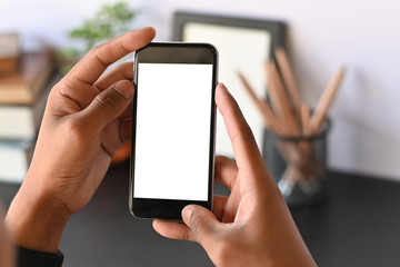 Cropped shot of smartphone on hands with empty screen on office desk.