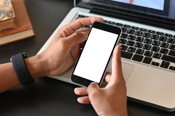 Man hands holding smart phone with blank copy space screen for your text message or information content, male reading text message on cell telephone during in urban setting.