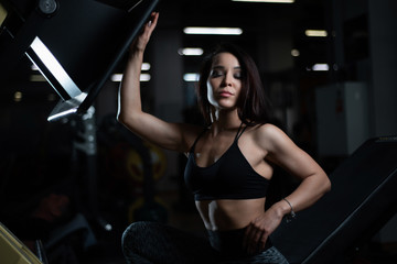 Fototapeta na wymiar Fitness girl posing in the gym, showing off her body and relaxing after a workout