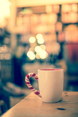 Steaming cup of thee on a wooden table, christmas time, blurry background