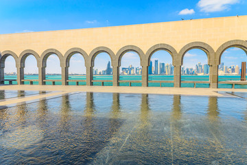 Modern skyscrapers of Doha West Bay skyline through series of arches along a walkway from museum in Qatari capital. Doha in Qatar seafront. Middle East, Arabian Peninsula in Persian Gulf.