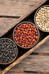 Organic white red and black pepper corns in wood display
