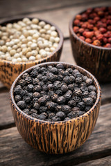 Organic white red and black pepper corns in wood display
