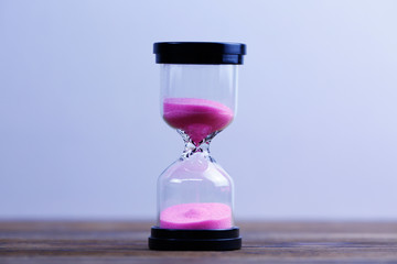 An hourglass on wooden background. Running out of time