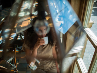 attractive girl with curly hair sits in a cafe at the table and drinks coffee
