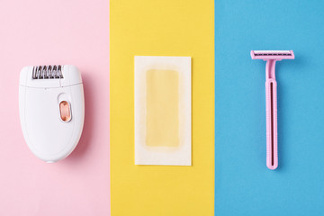 Epilator, razor and wax strips on color background