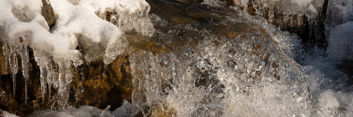 Water flowing in rapids over stone, in the winter mountains