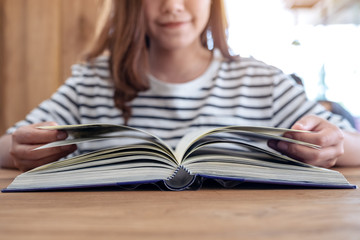 Closeup image of a beautiful asian woman holding and reading a book