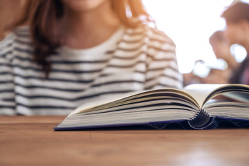 Closeup image of a woman and a book on wooden table