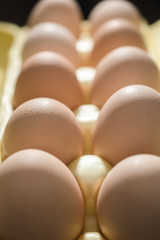 Chicken eggs lie in a yellow plastic tray.