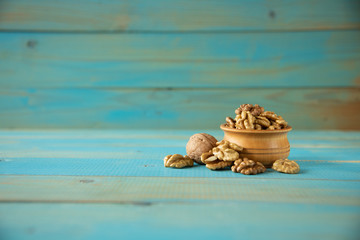 Walnuts on blue rustic table in wooden bowl