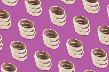 Diagonal rows of rolls of adhesive paper tape on purple background
