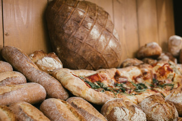 different fresh bread and pizza on the shelves in bakery. Selective focus