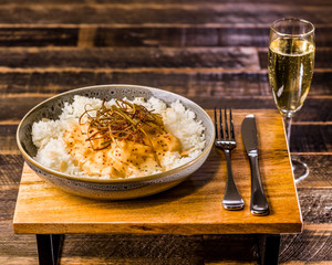 A bowl of honey mustard chicken served with white rice and almond flakes, presented on a wooden board