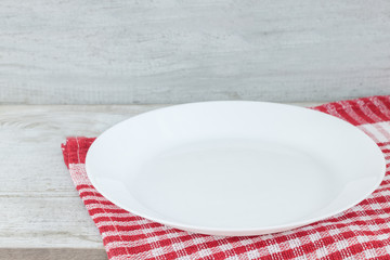 Empty plate on tablecloth or napkin on wooden table over cement background