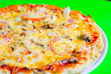 hot tasty fresh pizza on a plate close-up. green background