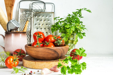 Food vegetables of different varieties of tomato in a bowl and on a white wooden table, preparation for preservation. Still life in a rustic style