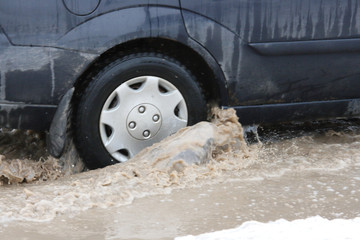 Splashing water from under the wheels of a car traveling through a puddle