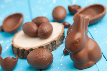 Chocolate Easter bunny, eggs and sweets on rustic background