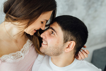 Obraz premium Laughing young people in pajamas playfully posing at sofa. Happy couple smiling in morning