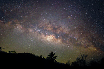 The Milky way illuminated on the dark sky over Silhouette mountains peak with trees