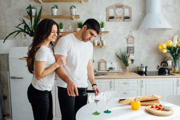 Smiling lovers drinking white wine in the kitchen