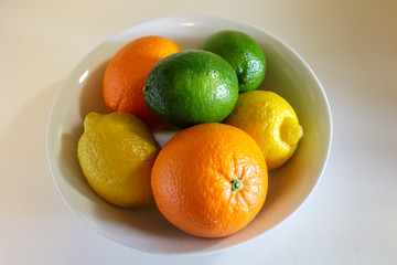 Citrus fruit in a white bowl. Lemons limes and oranges