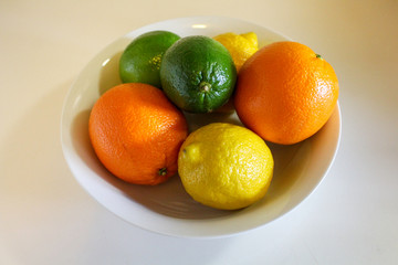 Citrus fruit in a white bowl. Lemons limes and oranges