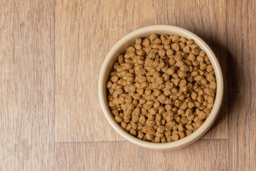Beige cat and dog food bowl on the floor. Top view