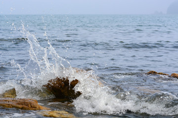 The wave breaks on the rock and forms a lot of spray