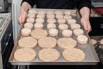 Closeup chef cook hands hold chicken cutlets for burgers. Bread crumbs on metal kitchen tray. Ingredients. Concept restaurant business, fast food, preparation tasty gastronomy, cooking, menu