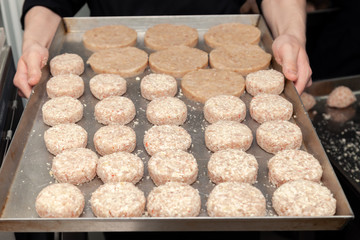 Closeup chef cook hands hold chicken cutlets for burgers. Bread crumbs on metal kitchen tray. Ingredients. Concept restaurant business, fast food, preparation tasty gastronomy, cooking, menu