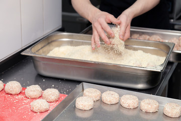 Chef hands creating, forming, breading chicken cutlet with knife on professional restaurant kitchen. Concept fast food business, preparation for cooking, menu, gastronomy, burgers, patty, meatballs