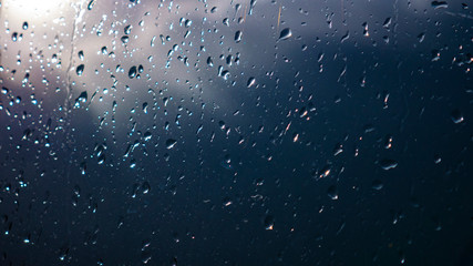 Raindrops on glass and blurred blue sky and clouds