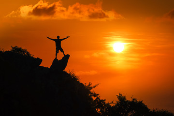 Man standing on the top of the mountain looking at red sky sunset