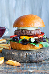 Venison burger in brioche bun with peppery leaf salad, onion, roast peppers and lingonberry sauce