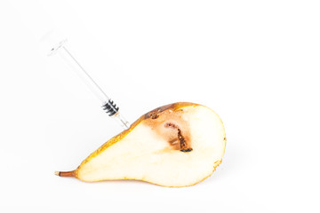 Close up Boring trace of a codling moth Cydia Pomonella, in a half middle wormy pear. On white background. With syringe. Concept non organic and genetically modified organism