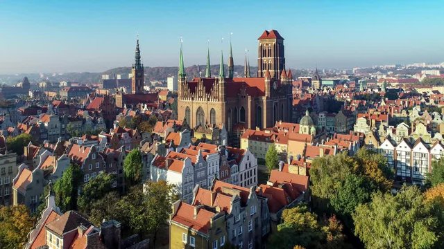 Gdansk, Poland. Old city with Gothic St. Mary church, city hall with clock tower and old historic houses. Aerial revealing video in sunrise light