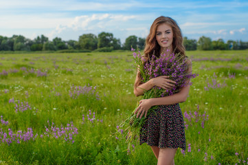 Girl in a field with lavender flowers in her hands.