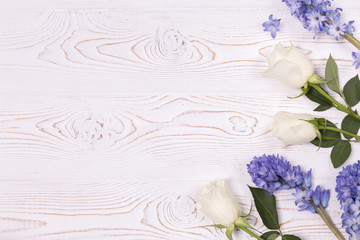 Top view on blue flowers of hyacinth and white roses on a white wooden table with space for text