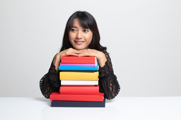 Happy young Asian woman read a book with books on table.