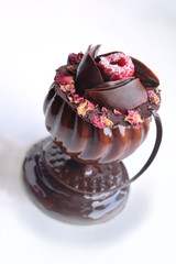 Glass shaped dessert with rose petals and raspberry on white background