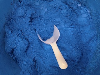 Close up of dry ultramarin pigment powder with a white spoon  - 255711258