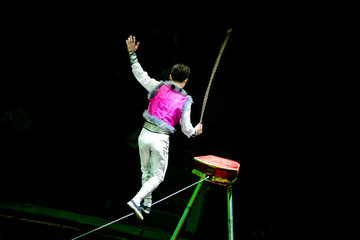 Acrobat walking on a rope during a performance in the circus  © licvin