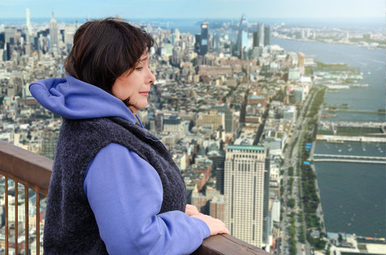 Woman suffers from a fear of heights. She is scared on the viewing platform above a big city.