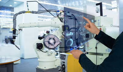 The engineer uses a futuristic projection touch screen to control robots in a smart factory. Smart...