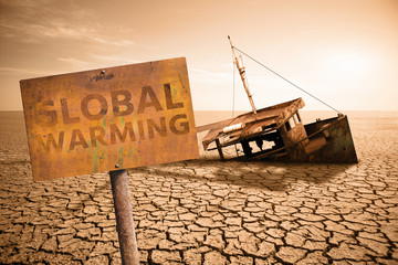 Rusty sign with text "Global warming" and old ship in a dried ocean.  Climate change concept.
